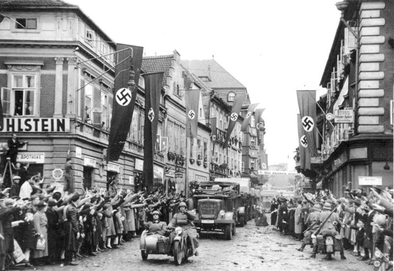 German mechanized troops enter Saaz. The streets are decorated with swastika flags and banners. 9.10.1938 14.30 Uhr. Saaz. Sudetenland