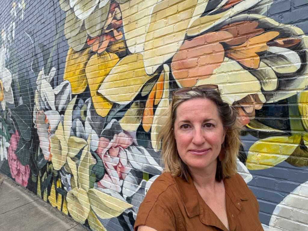 Woman standing in front of vibrant butterfly mural in Gloucester, Virginia.