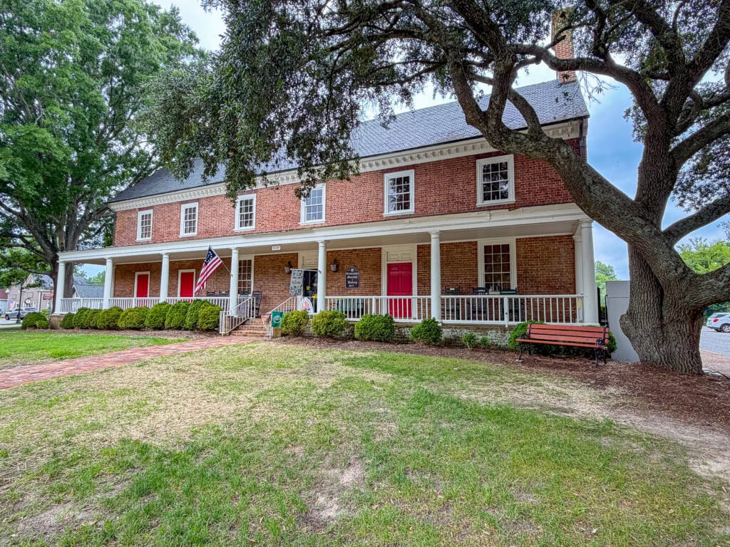 Historic brick house with large porch and mature trees in Gloucester, Virginia.